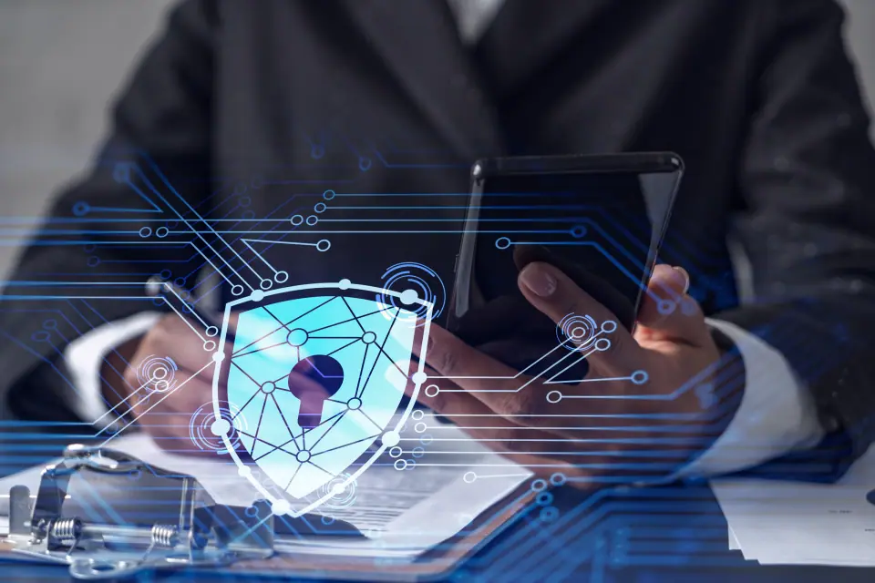African American businesswoman in formal wear signing the contract to prevent probability of risks in cyber security. Checking the phone. Padlock Hologram icons over the working desk.