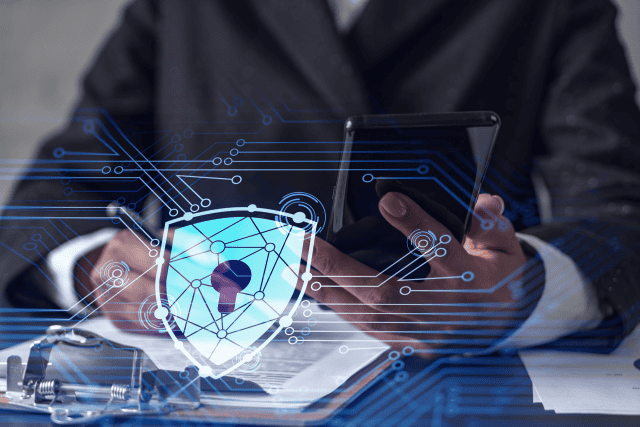 African American businesswoman in formal wear signing the contract to prevent probability of risks in cyber security. Checking the phone. Padlock Hologram icons over the working desk.