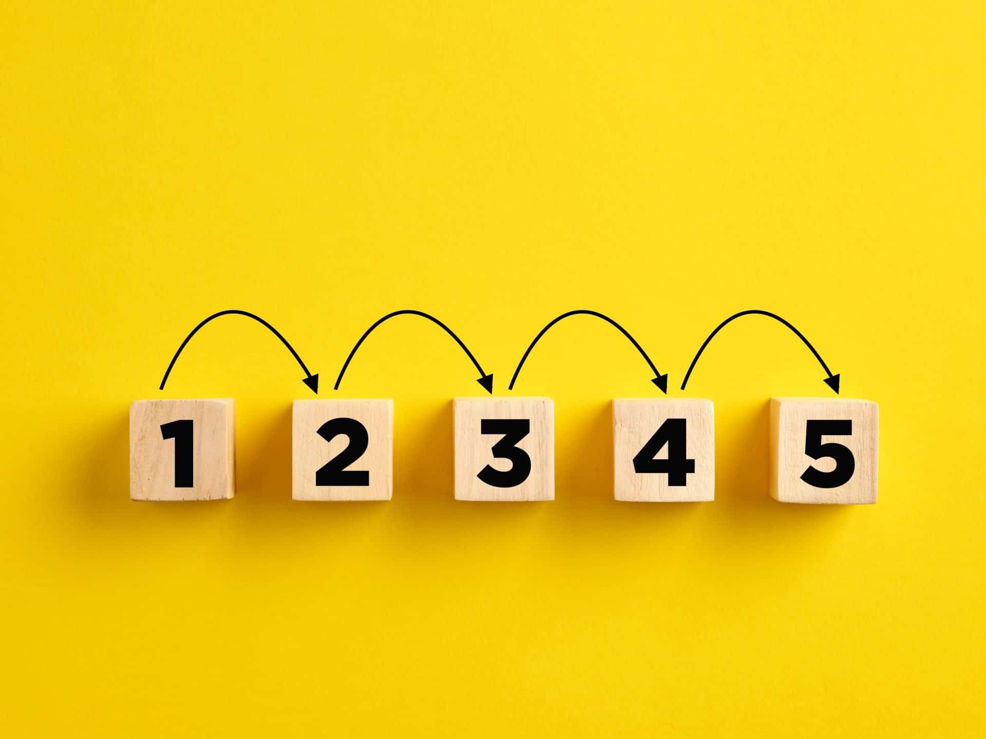 Step by step progress in business planning, following the procedures or problem solving concept. Numbers with arrows on wooden cubes.