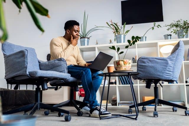 Young black men sitting in co-working space working while using laptop.