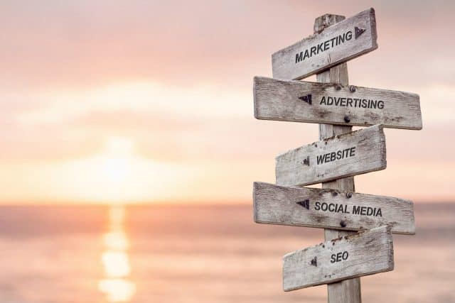 marketing advertising website social media seo text engraved on wooden signpost by the ocean during sunset seo agency